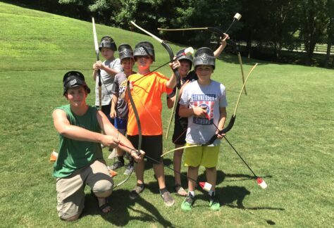 Deer Run Summer Volunteer with 5 boys at archery tag at Deer Run Camps & Retreats