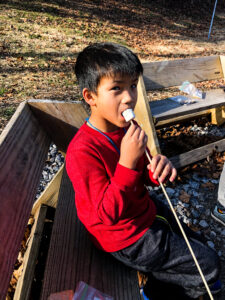 boy eating toasted marshmallow at Deer Run Winter Day Camp