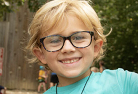 boy camper wearing glasses at climbing wall at Deer Run Camps & Retreats