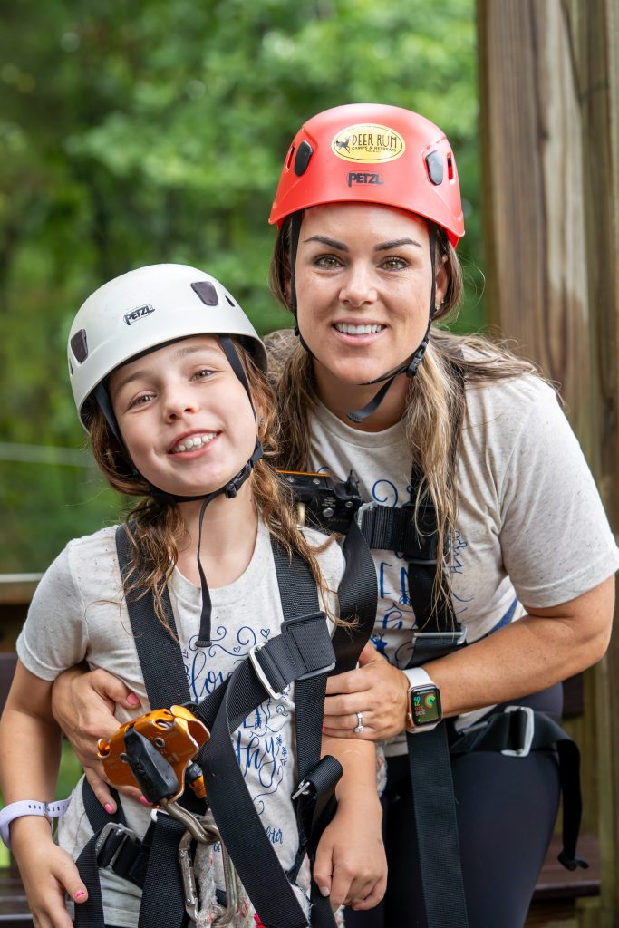 A Mother & Daughter smiling in harnesses and helmets at Deer Run Camps & Retreats Mother-Daughter Getaway Weekend