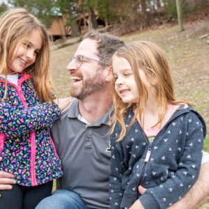 Dad smiling with his two daughters at Deer Run's Daddy Daughter picnic event.