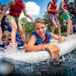 A day camp boy and several others having fun on the Lake Aqua Park at Deer Run Camps & Retreats