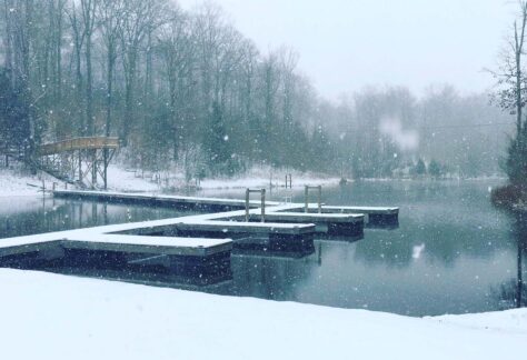 ground and floating docks covered in snow as it is falling at Spring Valley Lake at Deer Run Camps & Retreats