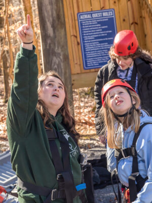 Full time Deer Run Camps & Retreats staff member explains the aerial quest high ropes activity to a camper.