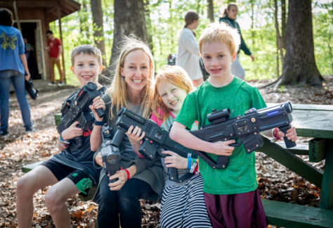 Mother and her children smile holding laser taggers at the laser tag arena during Deer Run Camps & retreats annual Family Day event.