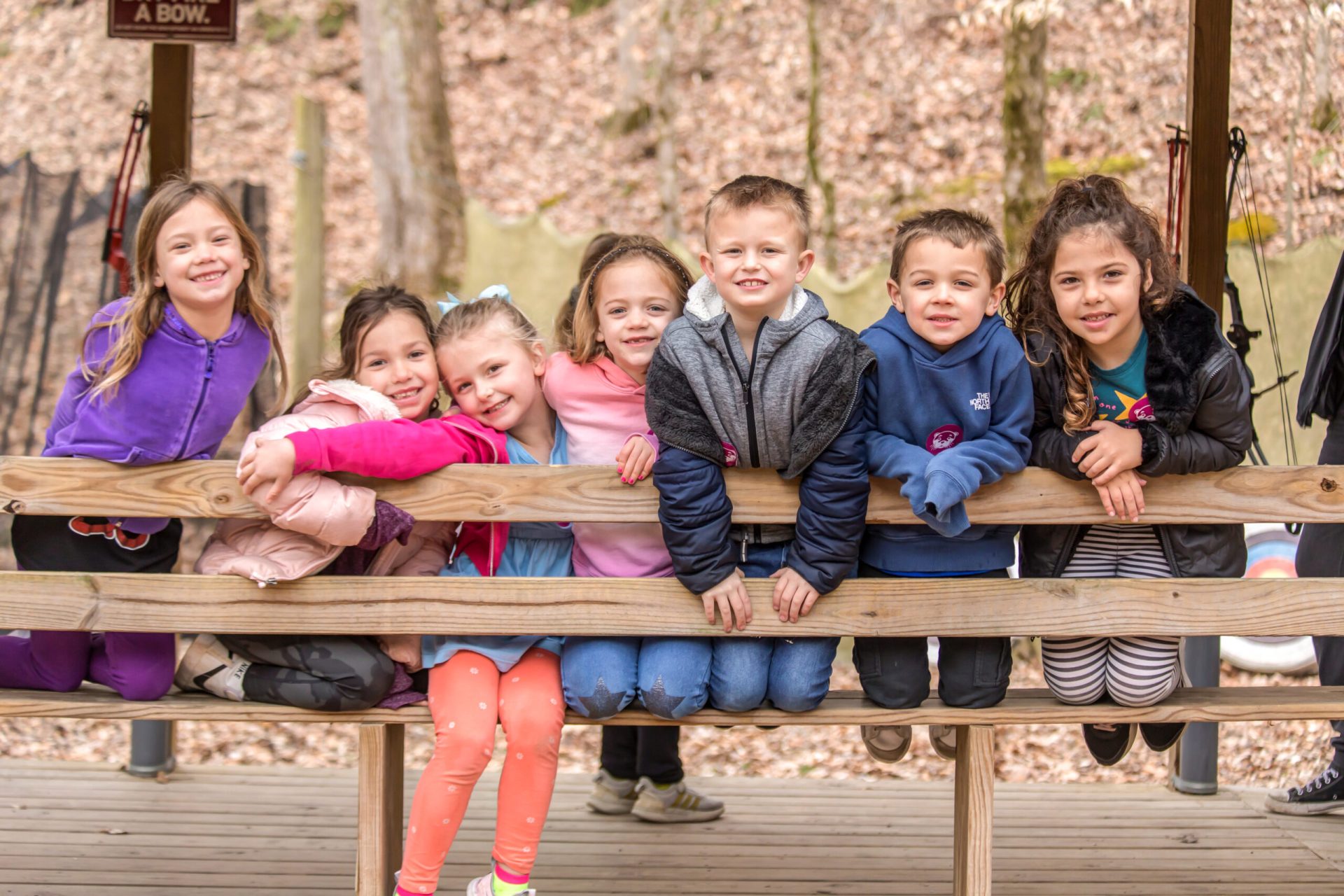 Several Winter Day Campers smiling for a picture at the Archery/BB range at Deer Run Camps & Retreats Winter Camp.