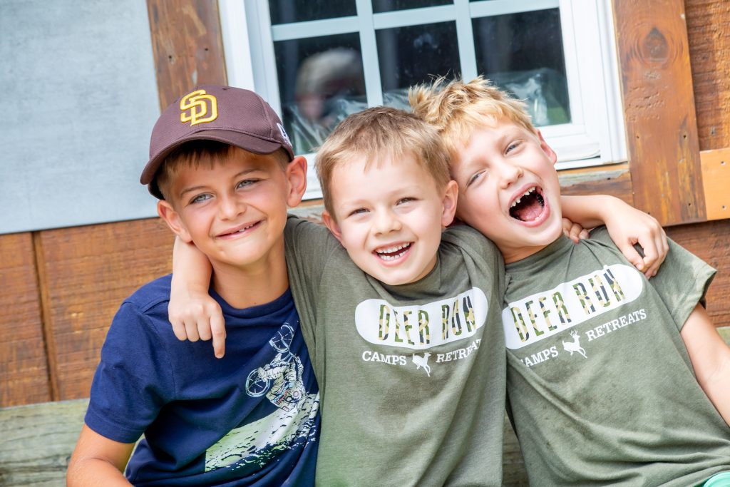 boys laughing and smiling with arms around each other at summer camp