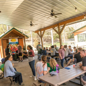 Deer Run Camps Open house event taking place- guests socialize at creekside veranda as staff greet and tell them about Summer Camps.