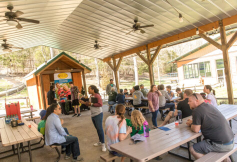Deer Run Camps Open house event taking place- guests socialize at creekside veranda as staff greet and tell them about Summer Camps.